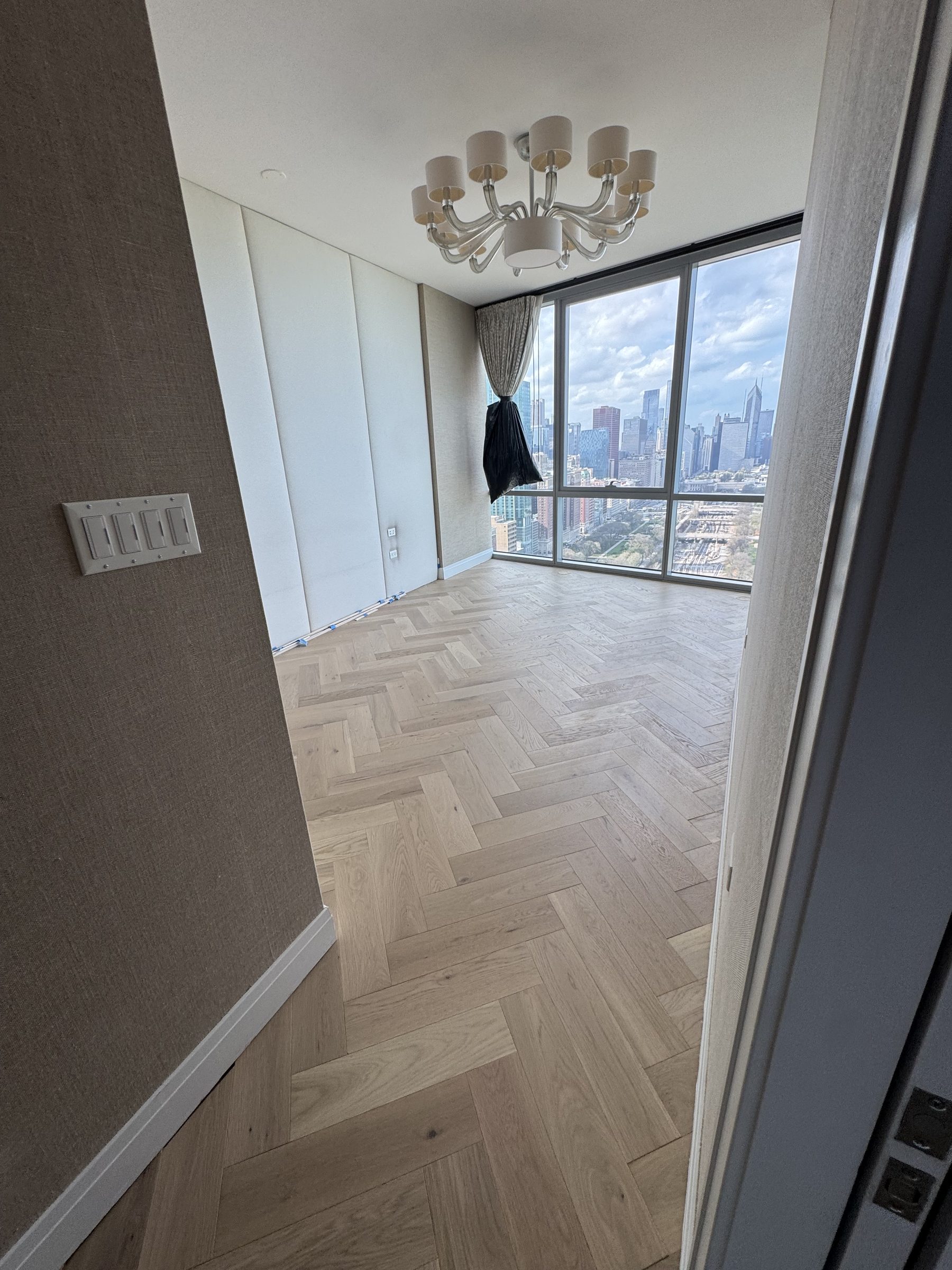 Herringbone hardwood bedroom with chandelier and city view